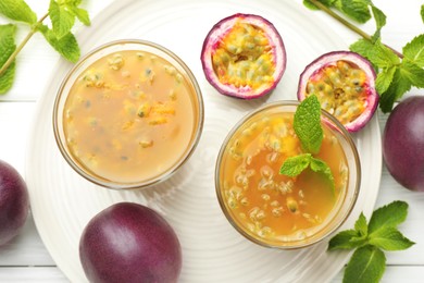 Photo of Tasty passion fruit drink with mint and fresh fruits on white wooden table, flat lay