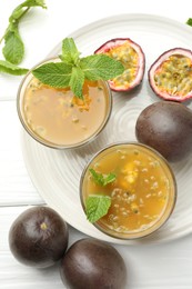 Photo of Tasty passion fruit drink with mint and fresh fruits on white wooden table, flat lay