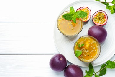 Photo of Tasty passion fruit drink with mint and fresh fruits on white wooden table, flat lay. Space for text