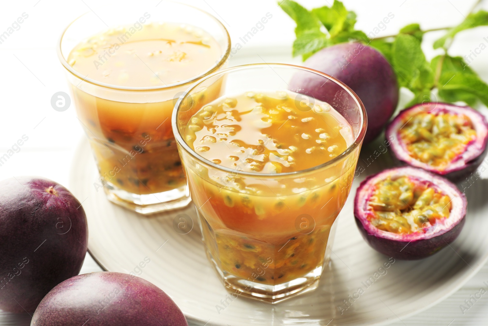 Photo of Tasty passion fruit drink and fresh fruits on white wooden table, closeup