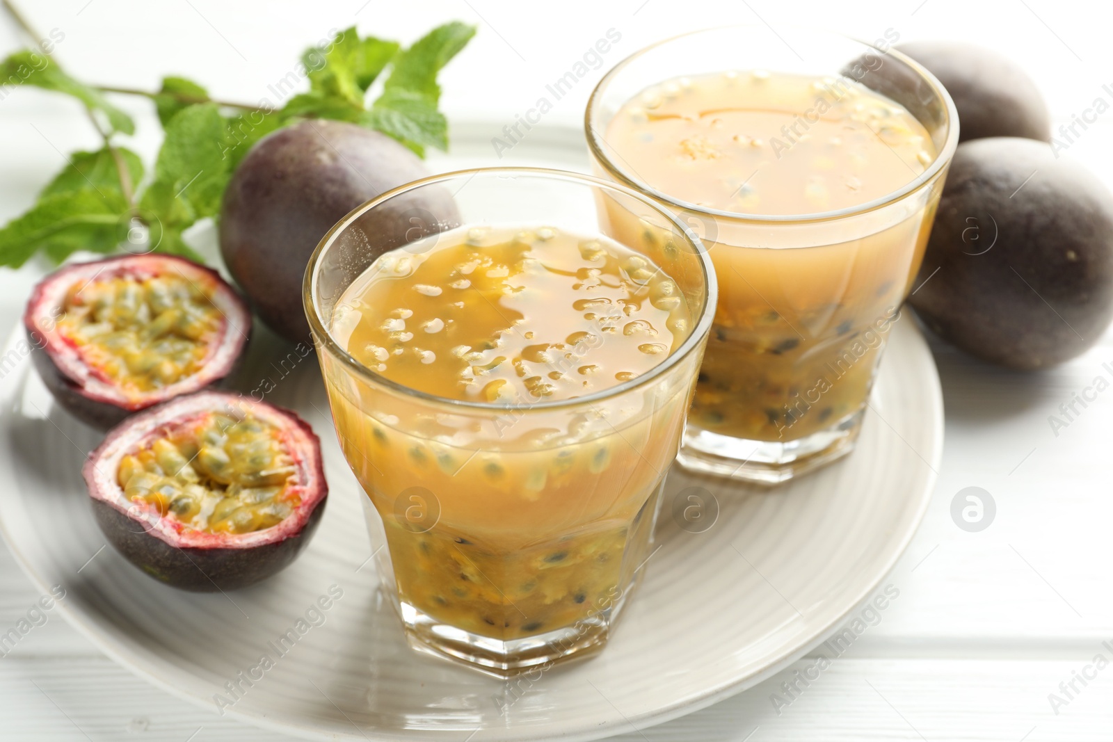 Photo of Tasty passion fruit drink and fresh fruits on white wooden table, closeup