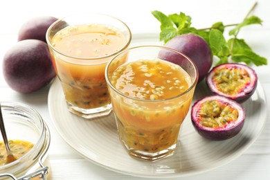 Photo of Tasty passion fruit drink and fresh fruits on white wooden table, closeup