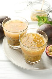 Photo of Tasty passion fruit drink and fresh fruits on white wooden table, closeup