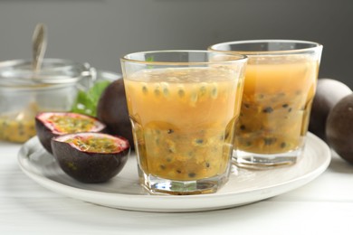 Photo of Tasty passion fruit drink and fresh fruits on white wooden table, closeup