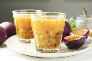 Photo of Tasty passion fruit drink and fresh fruits on white wooden table, closeup