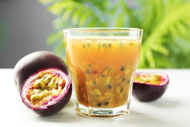 Photo of Tasty passion fruit drink and fresh fruits on white wooden table, closeup