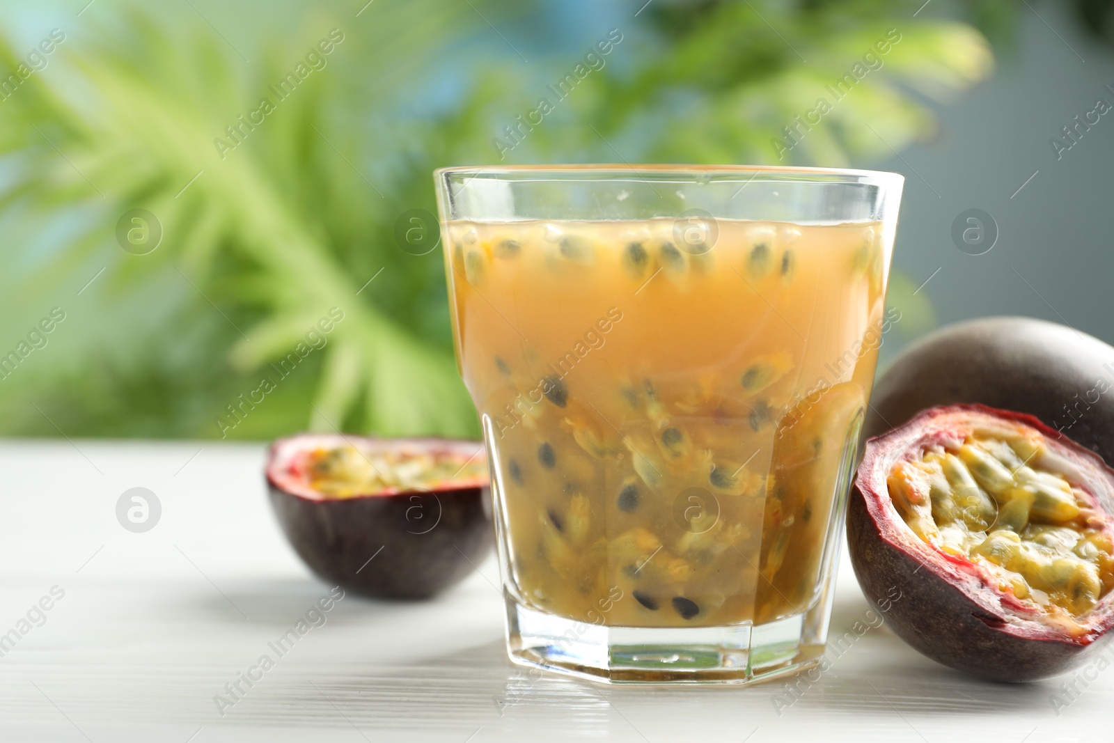 Photo of Tasty passion fruit drink and fresh fruits on white wooden table, closeup