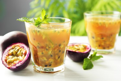 Photo of Tasty passion fruit drink and fresh fruits on white wooden table, closeup