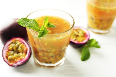 Photo of Tasty passion fruit drink and fresh fruits on white wooden table, closeup