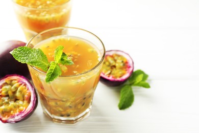 Photo of Tasty passion fruit drink and fresh fruits on white wooden table, closeup. Space for text
