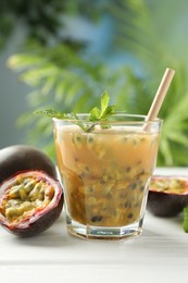 Photo of Tasty passion fruit drink and fresh fruits on white wooden table, closeup