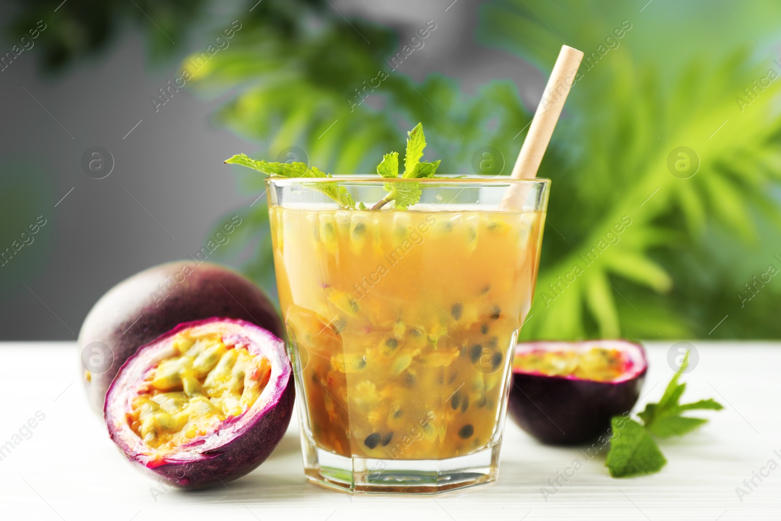 Photo of Tasty passion fruit drink and fresh fruits on white wooden table, closeup