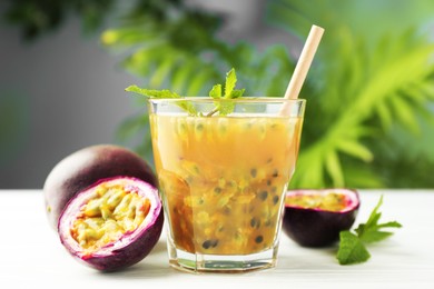 Photo of Tasty passion fruit drink and fresh fruits on white wooden table, closeup