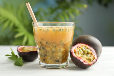 Photo of Tasty passion fruit drink and fresh fruits on white wooden table, closeup