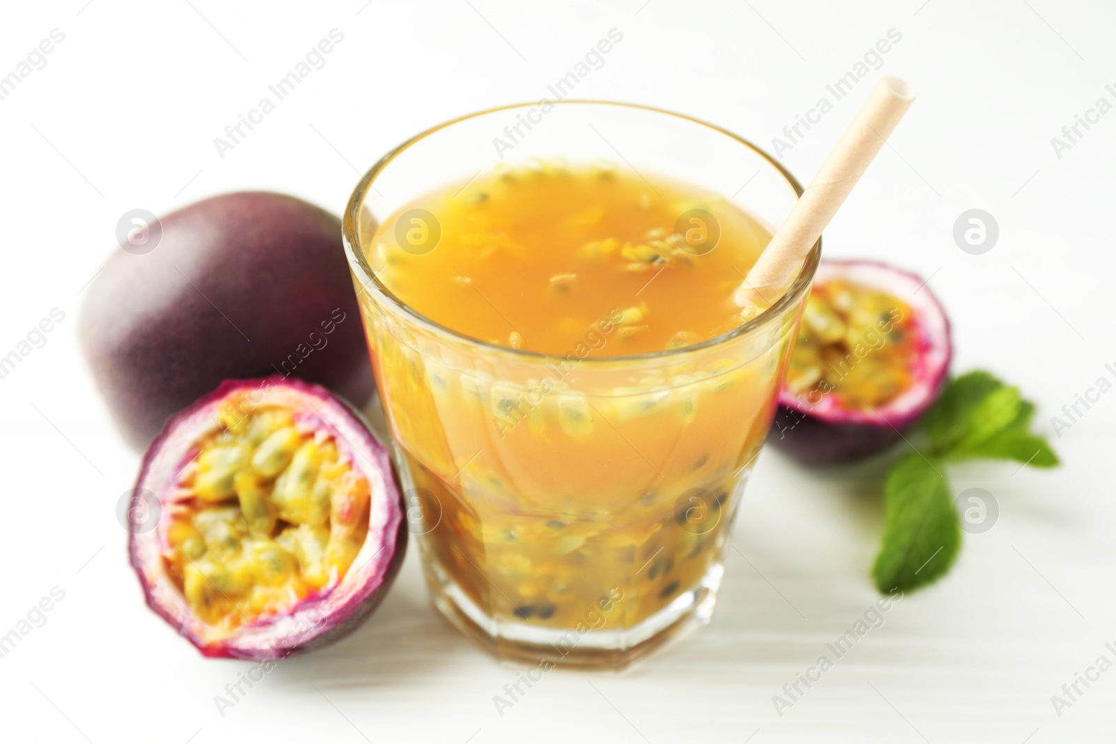 Photo of Tasty passion fruit drink and fresh fruits on white wooden table, closeup