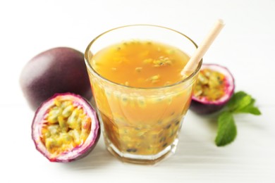 Photo of Tasty passion fruit drink and fresh fruits on white wooden table, closeup