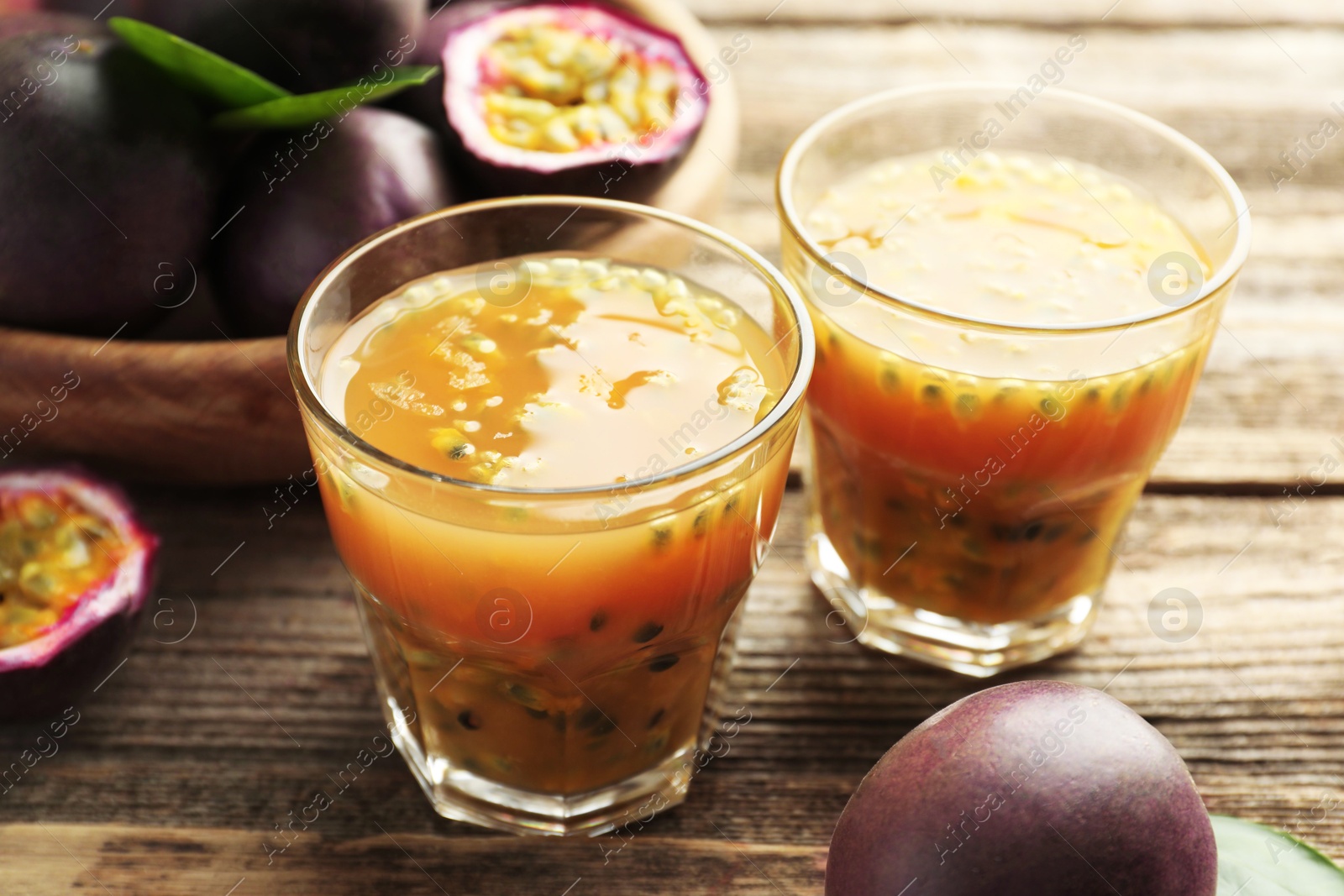 Photo of Tasty passion fruit drink and fresh fruits on wooden table, closeup
