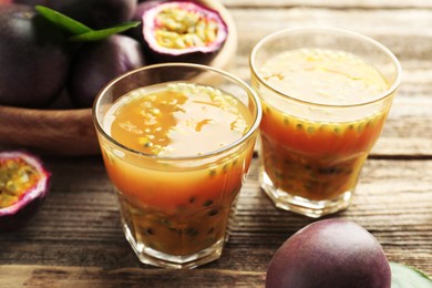 Photo of Tasty passion fruit drink and fresh fruits on wooden table, closeup