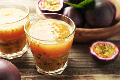 Photo of Tasty passion fruit drink and fresh fruits on wooden table, closeup