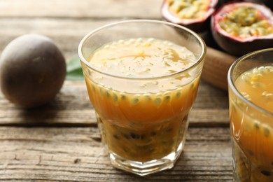 Photo of Tasty passion fruit drink and fresh fruits on wooden table, closeup