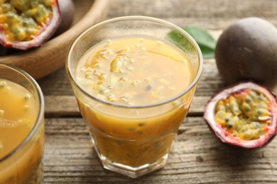 Photo of Tasty passion fruit drink and fresh fruits on wooden table, closeup