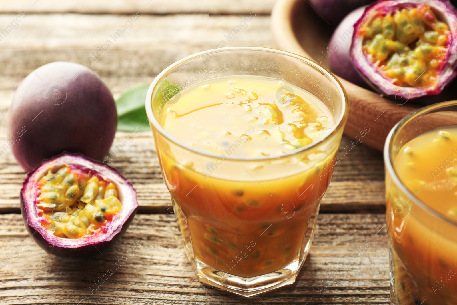 Photo of Tasty passion fruit drink and fresh fruits on wooden table, closeup