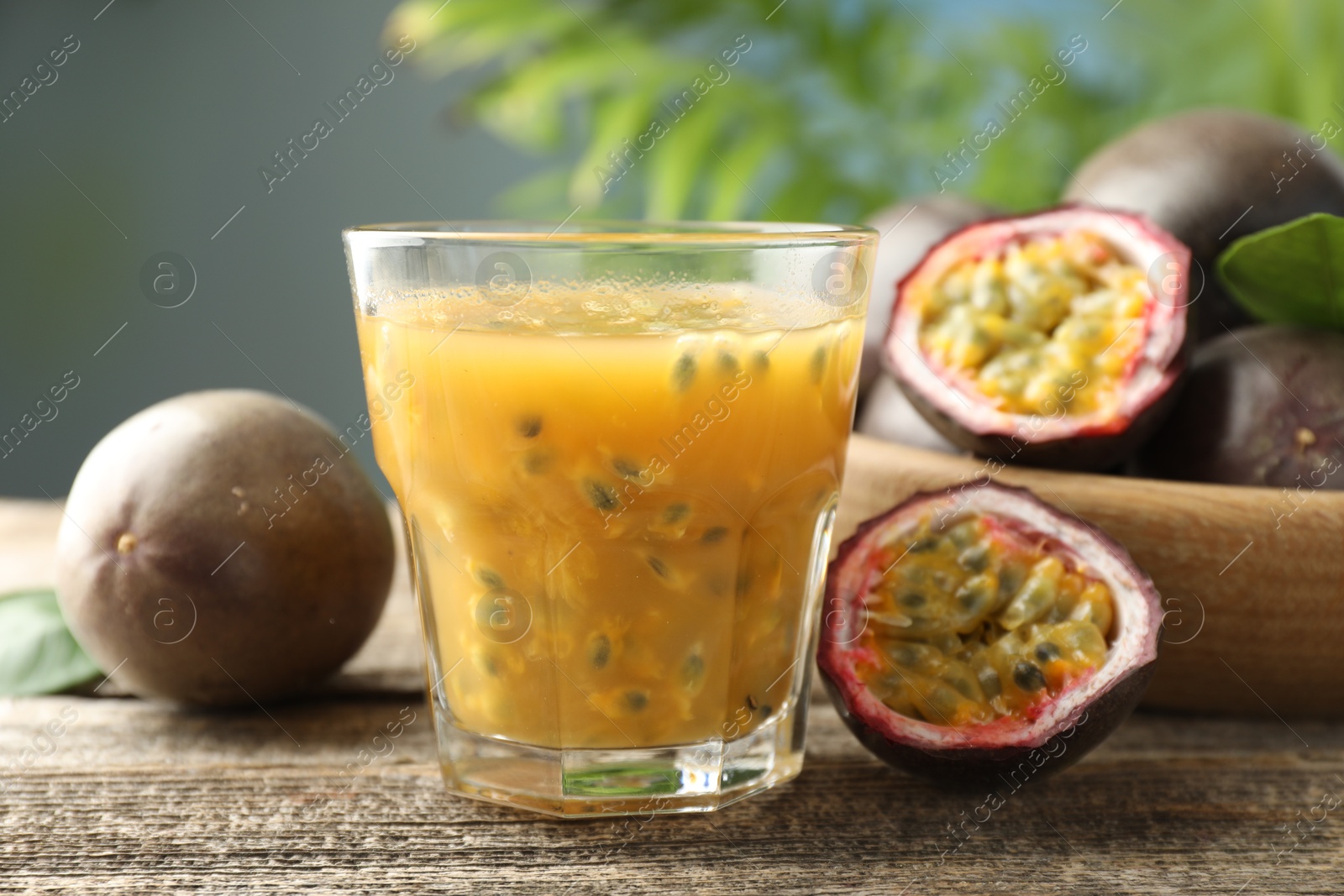 Photo of Tasty passion fruit drink and fresh fruits on wooden table, closeup