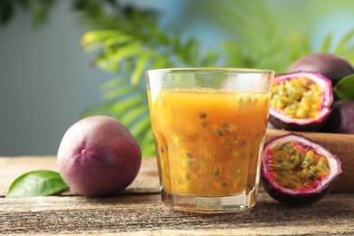 Photo of Tasty passion fruit drink and fresh fruits on wooden table, closeup