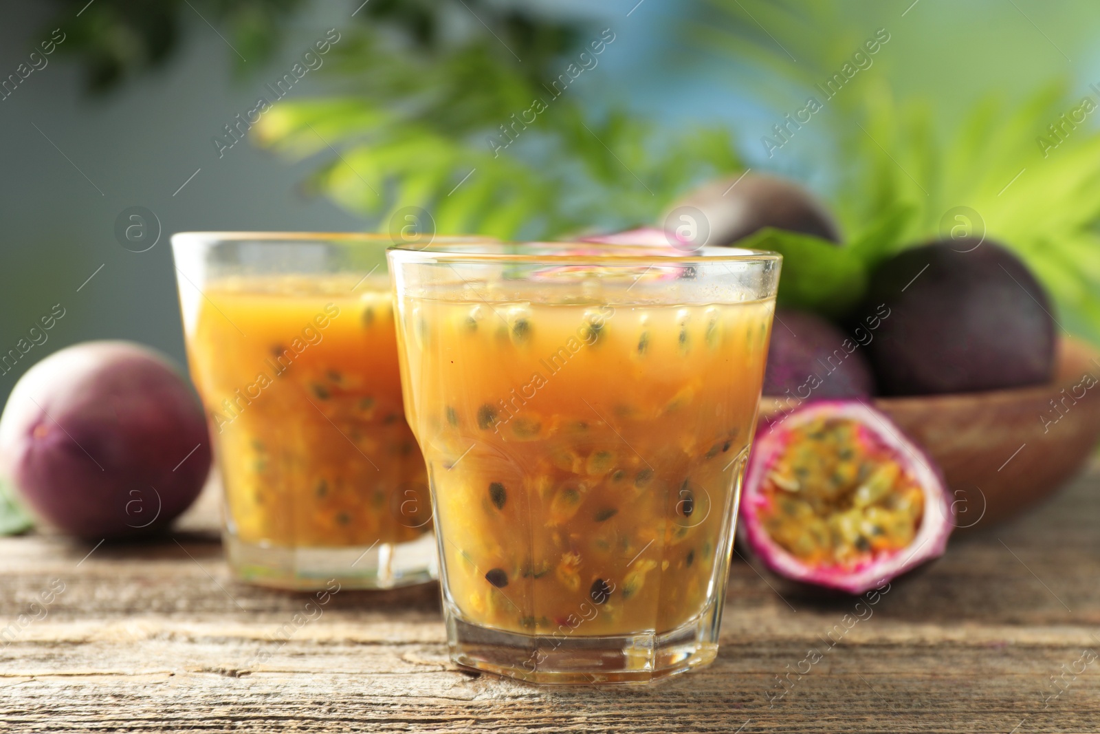 Photo of Tasty passion fruit drink and fresh fruits on wooden table, closeup