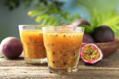 Photo of Tasty passion fruit drink and fresh fruits on wooden table, closeup