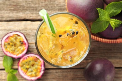 Photo of Tasty passion fruit drink with mint and fresh fruits on wooden table, flat lay