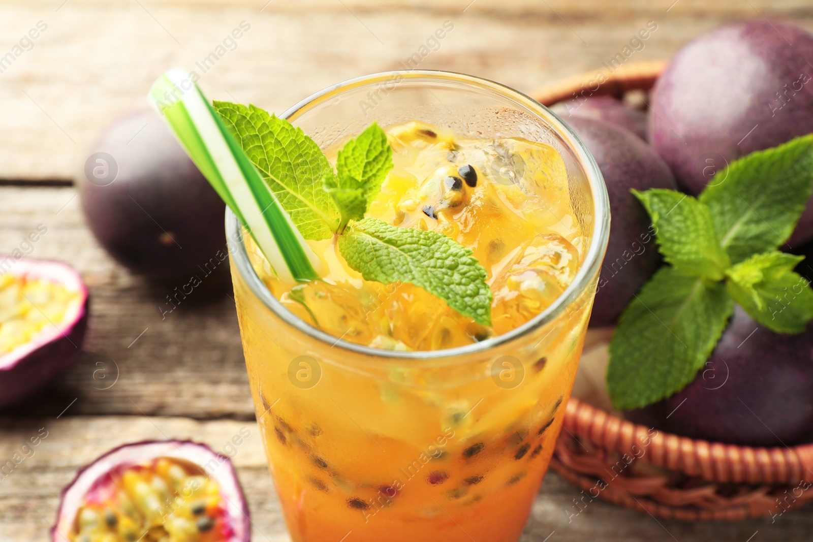 Photo of Tasty passion fruit drink with mint and fresh fruits on wooden table, closeup