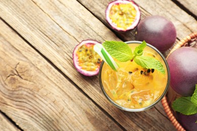 Photo of Tasty passion fruit drink with mint and fresh fruits on wooden table, flat lay. Space for text