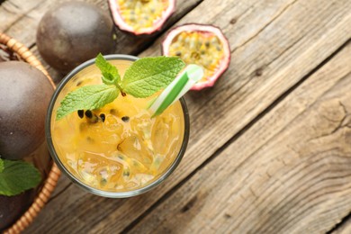 Photo of Tasty passion fruit drink with mint and fresh fruits on wooden table, flat lay. Space for text