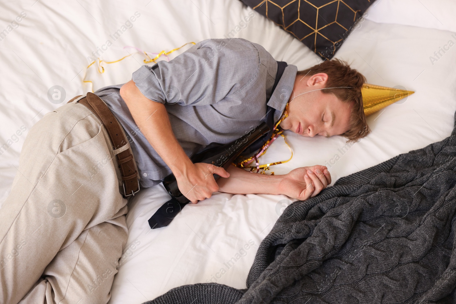 Man with bottle of alcohol suffering from hangover on bed indoors, above view Photo of Man with bottle of alcohol suffering from hangover on bed indoors, above view