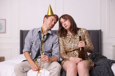 Photo of People with alcohol suffering from hangover on bed indoors