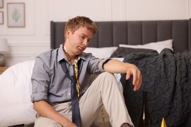Photo of Man suffering from hangover near bed indoors