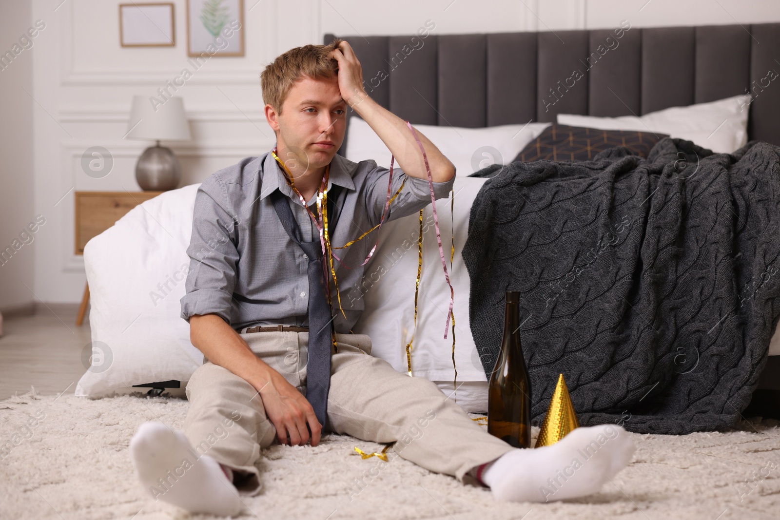 Man suffering from hangover near bed indoors Photo of Man suffering from hangover near bed indoors