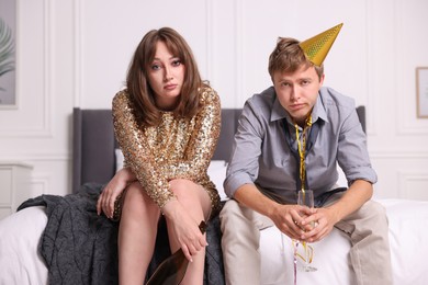 Photo of People with alcohol suffering from hangover on bed indoors