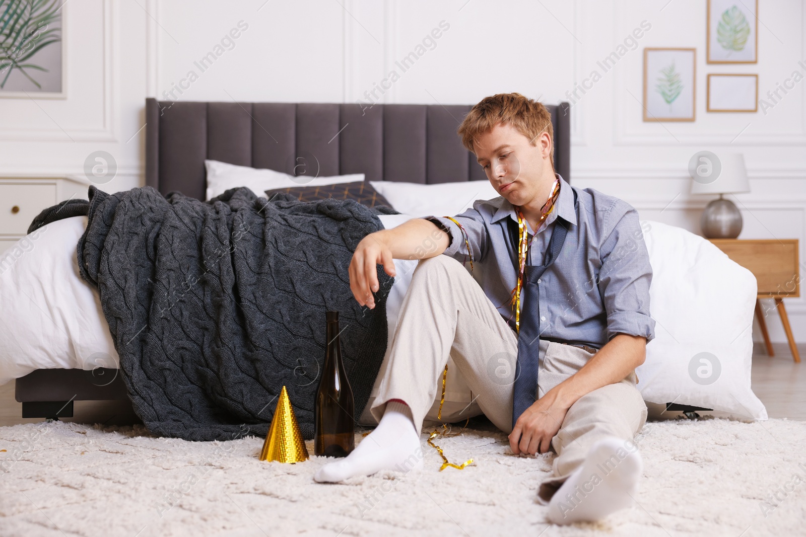 Man suffering from hangover near bed indoors Photo of Man suffering from hangover near bed indoors