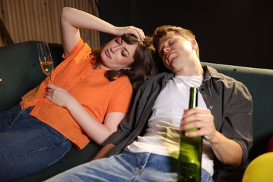 Photo of People with alcohol suffering from hangover on sofa in messy room after party