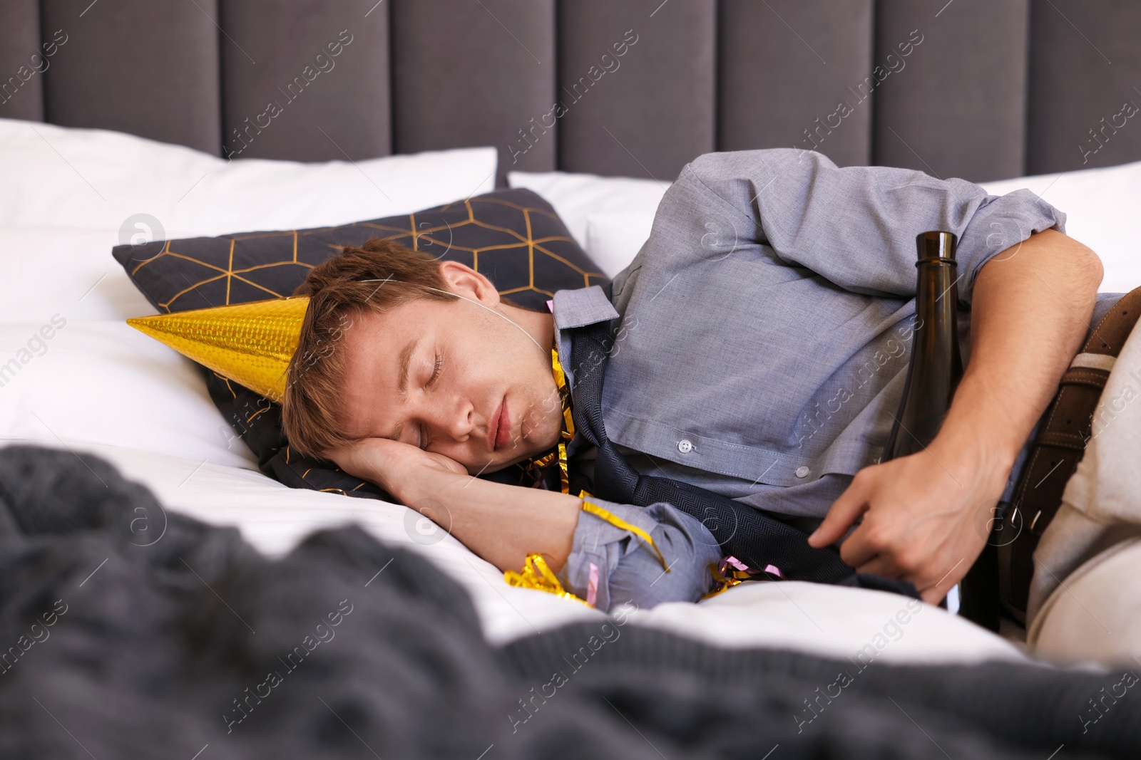 Man with alcohol suffering from hangover on bed indoors Photo of Man with alcohol suffering from hangover on bed indoors