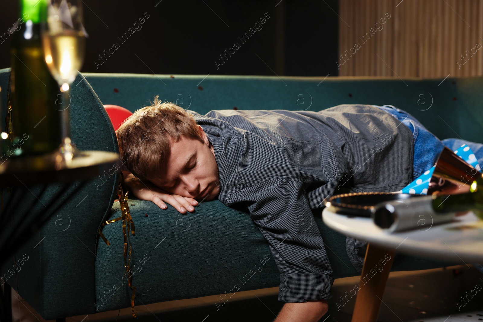 Man suffering from hangover on sofa in messy room after party Photo of Man suffering from hangover on sofa in messy room after party