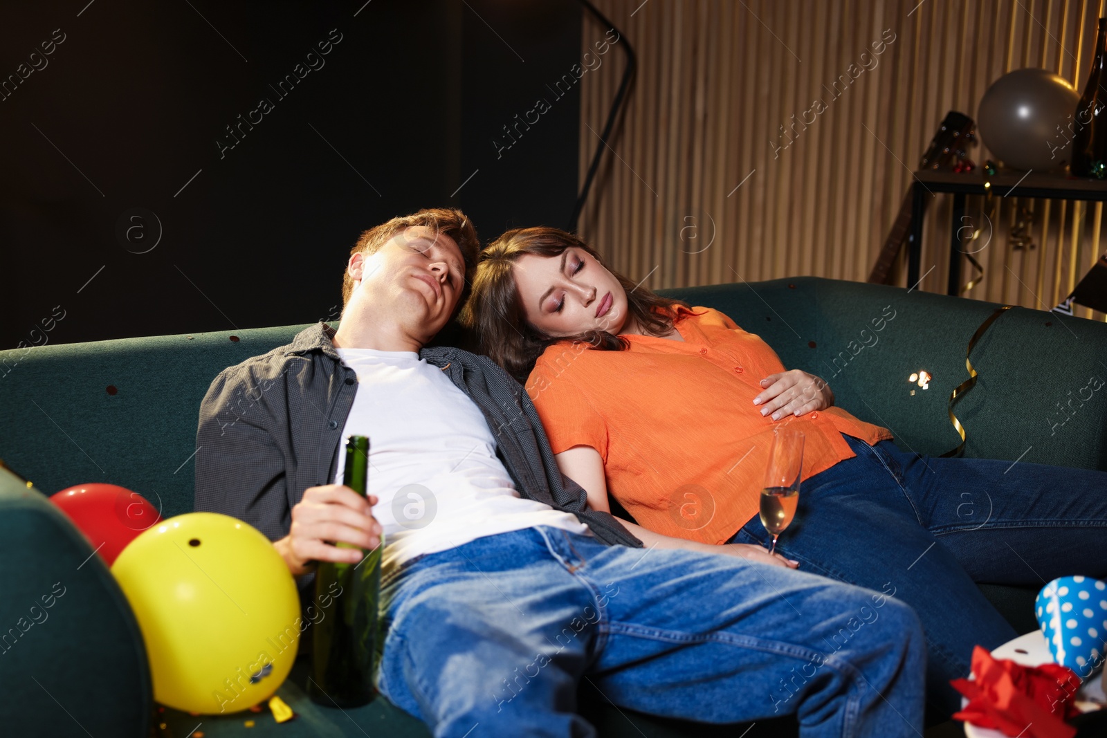 People with alcohol suffering from hangover on sofa in messy room after party Photo of People with alcohol suffering from hangover on sofa in messy room after party