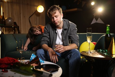 Photo of People suffering from hangover on sofa in messy room after party, selective focus