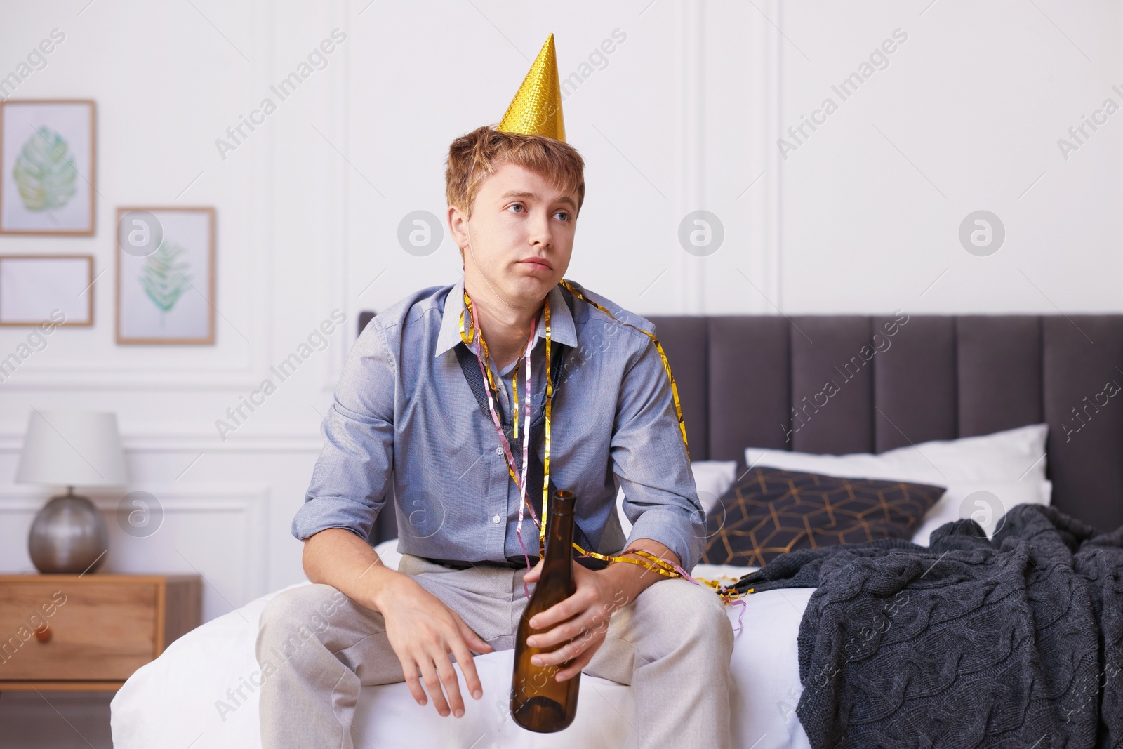 Man with alcohol suffering from hangover on bed indoors Photo of Man with alcohol suffering from hangover on bed indoors