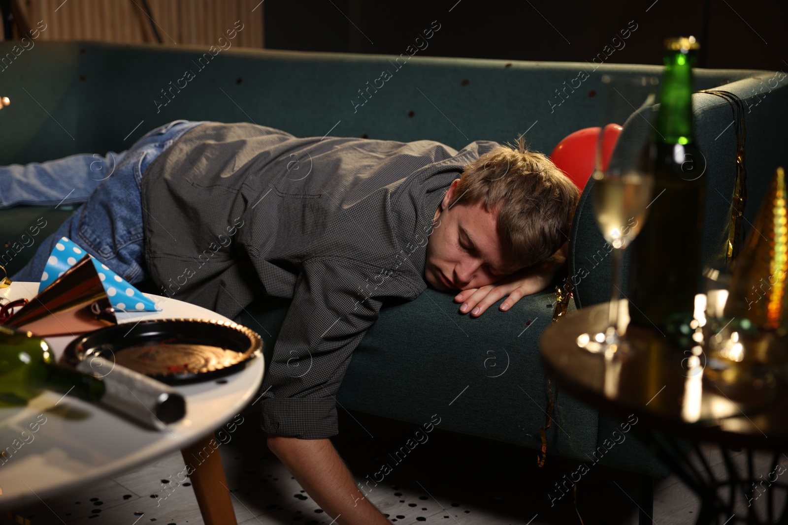 Man suffering from hangover on sofa in messy room after party Photo of Man suffering from hangover on sofa in messy room after party