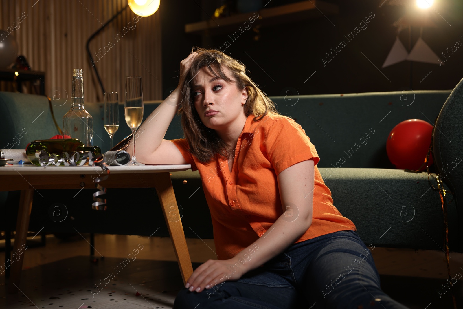Woman suffering from hangover in messy room after party Photo of Woman suffering from hangover in messy room after party