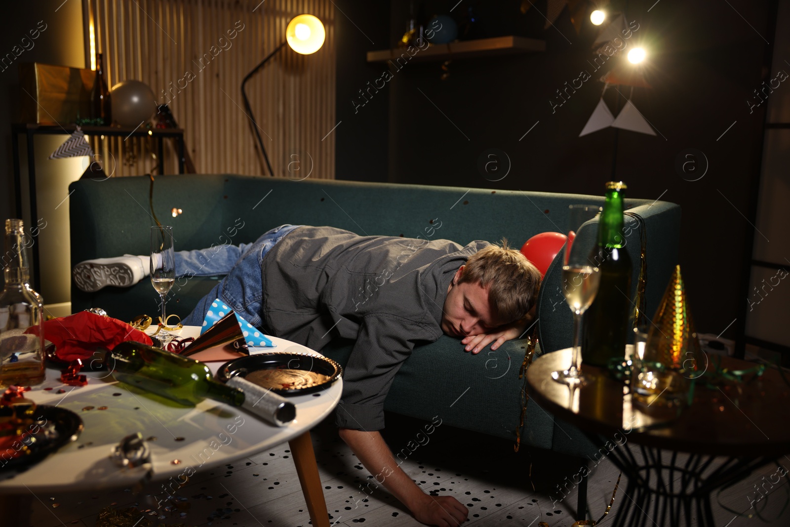 Man suffering from hangover on sofa in messy room after party Photo of Man suffering from hangover on sofa in messy room after party
