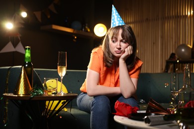 Photo of Woman suffering from hangover on sofa in messy room after party